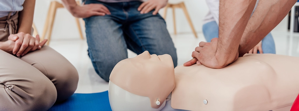 CPR dummy on the floor with hands on chest practicing compressions