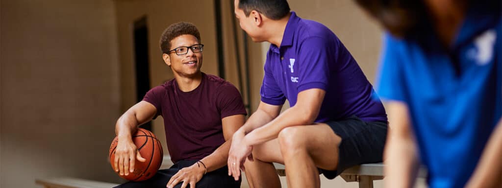man holding a basketball talking with his coach