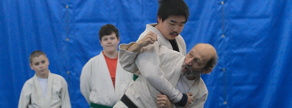 An instructor showing a student how to perform a judo technique at the keene family YMCA