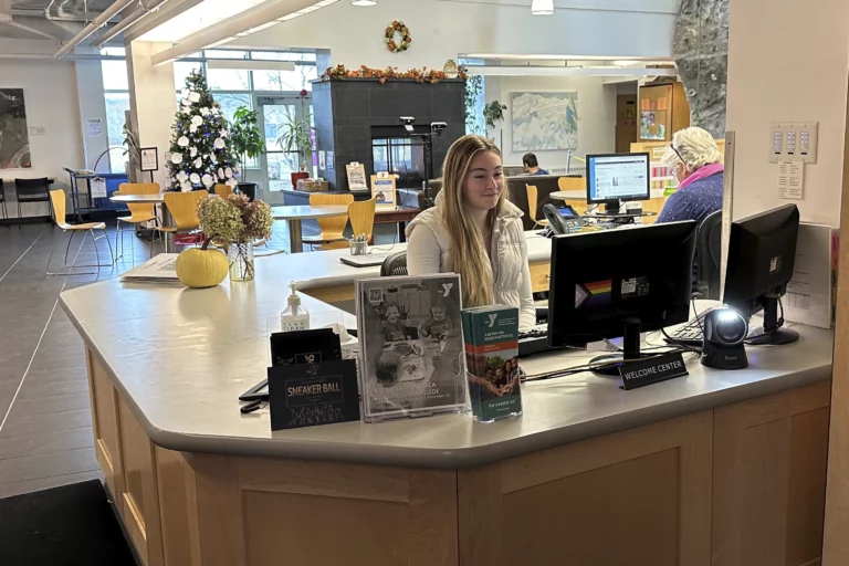 a smiling keene family YMCA employee sitting at the welcome center desk