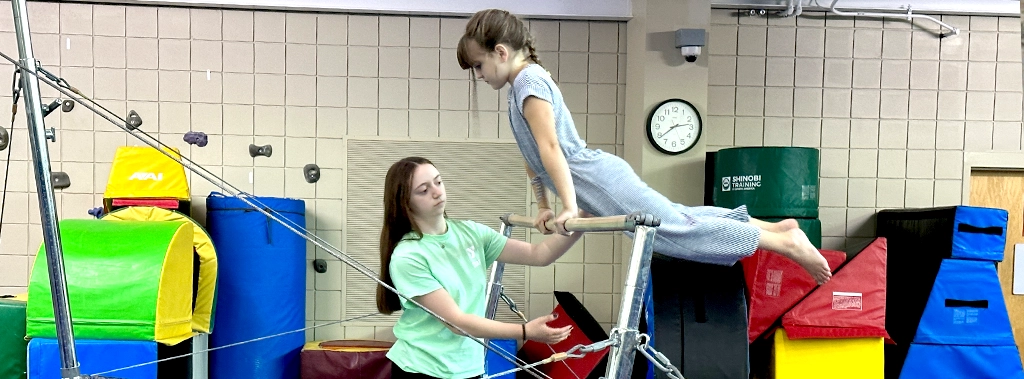 an instructor and child working together during a gymnastics class at the Y