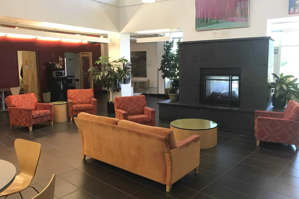 the keene family ymca lobby area with a fireplace, comfortable chairs, and couch