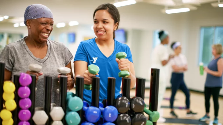 ymca staff member and woman standing with weights