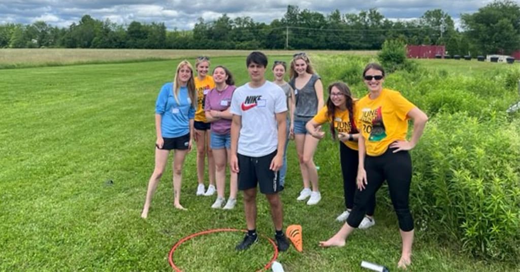 A group of summer camp counselors standing in the field at the Y